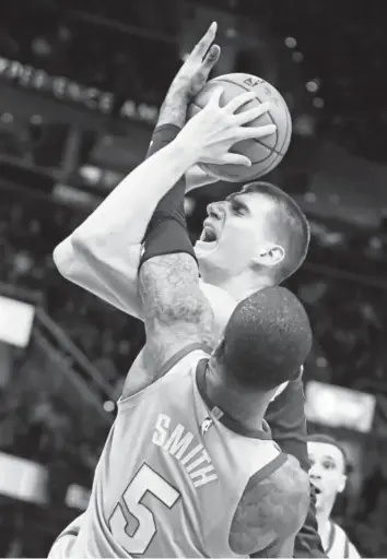  ?? Tony Dejak, The Associated Press ?? Cavaliers guard J.R. Smith tries to block Nuggets center Nikola Jokic from scoring Saturday night in Cleveland. Jokic contribute­d nine points, eight assists and seven rebounds to Denver’s 126-117 victory.