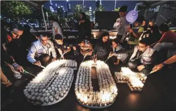  ?? A.K Kallouche/Gulf News ?? Left: Burj Khalifa goes dark during Earth hour yesterday. Above: People light candles to mark Earth Hour at the Festival Bay Avenue Park in Dubai yesterday.