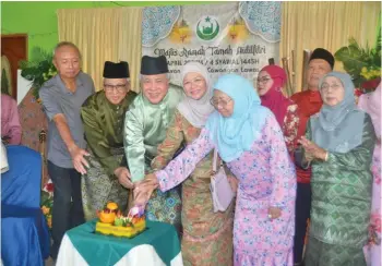  ?? ?? Awang Tengah (third left) and Dayang Morliah, on his left, join others in the cake-cutting ceremony.