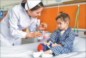  ?? LIU XIN / CHINA NEWS SERVICE ?? A nurse interacts with a girl from Afghanista­n who has congenital heart disease at The First Affiliated Hospital of Xinjiang Medical University in Urumqi, Xinjiang Uygur autonomous region, on Tuesday. The Red Cross Society of China has arranged free corrective surgery for 100 Afghan children with the condition.