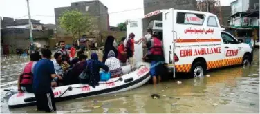 ?? Agence France-presse ?? ±
Edhi volunteers bring a boat to evacuate stranded people along a flooded street after heavy monsoon rainfall in Karachi on Monday.