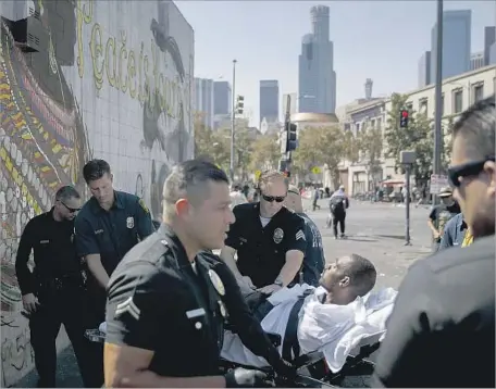  ?? Patrick T. Fallon For The Times ?? A MAN who fell ill on downtown Los Angeles’ skid row is taken to a hospital by Fire Department paramedics and LAPD officers. Since last week, more than 50 people on skid row have been hospitaliz­ed, many suspected of ingesting the synthetic drug known...