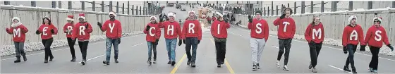  ??  ?? A Christmas greeting is spelled out by walkers along the Weber Street route of the annual Santa Claus parade on Saturday.