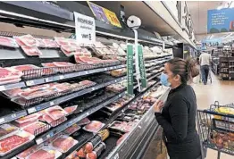  ?? JEFF AMY/AP ?? A woman shops Tuesday at a Kroger store in Atlanta. The chain is limiting meat sales.