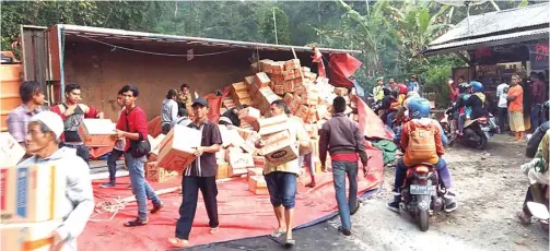  ?? POLSEK KALIBARU FOR JAWA POS RADAR BANYUWANGI ?? EVAKUASI: Polisi dan warga mengevakua­si muatan truk yang berserak di Jalan Raya Kumitir, Desa Kalibaru Manis, Kecamatan Kalibaru, kemarin.