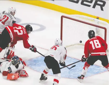  ?? GREG SOUTHAM ?? Canada's Dylan Cozens shovels the puck past Switzerlan­d goalie Noah Patenaude during second-period action at the world juniors Tuesday in Edmonton. Team Canada scored four times in the second period to break open a close contest and remain unbeaten through three starts.