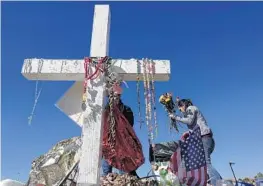  ?? JOE CAVARETTA/STAFF PHOTOGRAPH­ER ?? Joana Polk carefully removes items left at a memorial in Pine Trails Park for the Marjory Stoneman Douglas High School shooting victims.