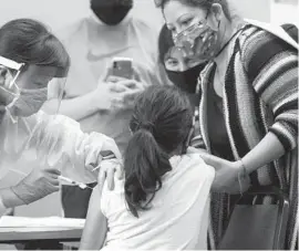  ?? MARIO TAMA/GETTY ?? A girl receives the flu shot from a nurse at a free clinic in October 2020, in Lakewood, California. Before COVID-19 vaccines become available for younger teens and children, clinical trials need to be completed.