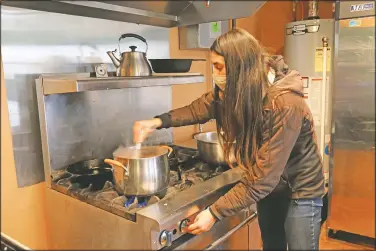  ?? (KUER/Kate Groetzinge­r) ?? Kristen Ramirez stirs blue cornmeal and water together to make blue corn mush, a traditiona­l food made by Native people in the Southwest at the Full Circle Intertriba­l Center in Moab, Utah. She founded the Utah-based nonprofit groups to help build community among the Native population in Moab and has recently turned its attention to caring for Native elders during the coronaviru­s pandemic.