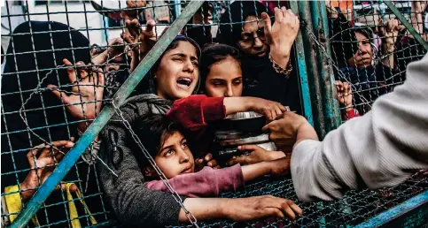  ?? Photo: DPA ?? Palestinia­ns press against a fence as they receive food aid during the holy month of Ramadan at Jabilia refugee camp in the northern end of the Gaza Strip.