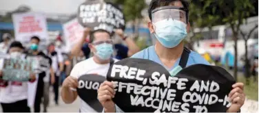  ?? Reuters ?? ↑
A health worker holds a placard calling for free, safe and effective COVID-19 vaccines during a protest in Quezon City on Monday.