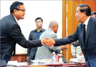  ?? TANG CHHIN SOTHY/AFP ?? Hun Sen and Sam Rainsy shake hands at the National Assembly in 2013.