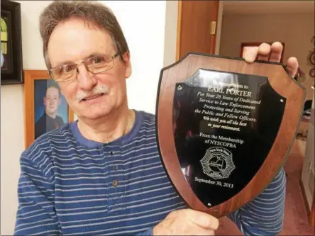  ?? PAUL POST PHOTO ?? Earl Porter of Greenfield displays the plaque he was awarded for 26 years of service as a state correction­s officer. In 1988, he was stabbed by an inmate an almost died while working at a maximum-security prison.