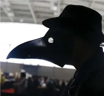  ??  ?? NOT QUITE SO BAD: Malloy Logan of Freetown wears a Renaissanc­e plague doctor’s mask while strolling through the Boston Convention and Exposition Center.