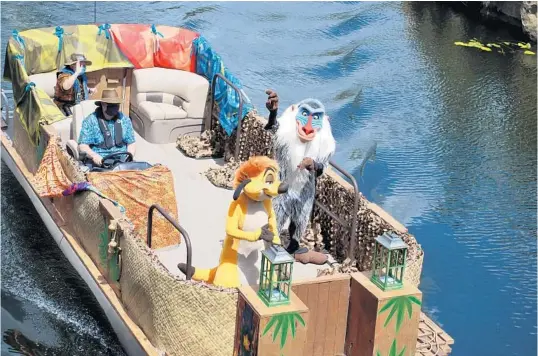  ?? KATHLEEN CHRISTIANS­EN/ORLANDO SENTINEL ?? Rafiki and Timon from “The Lion King” interact with guests from a social distance aboard a boat inside Disney’s Animal Kingdom on July 9, 2020.