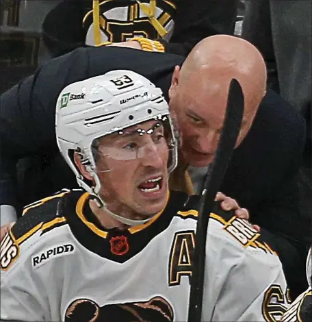  ?? STUART CAHILL — BOSTON HERALD ?? Bruins left wing Brad Marchand and head coach Jim Montgomery chat after the Bruins scored. Boston rolled to a 6-1 win over Chicago at the TD Garden.