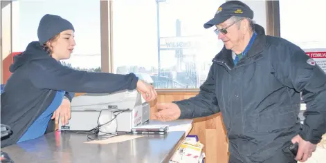  ?? KATHERINE HUNT/THE GUARDIAN ?? Store clerk Emily Gass hands change back to long-time regular customer Francis Gorveatt after he put gas in his vehicle on Tuesday.