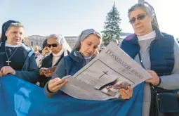  ?? DOMENICO STINELLIS/AP ?? Nuns read about the death of Pope Emeritus Benedict XVI as they wait Sunday for Pope Francis to appear at his window overlookin­g St. Peter’s Square.