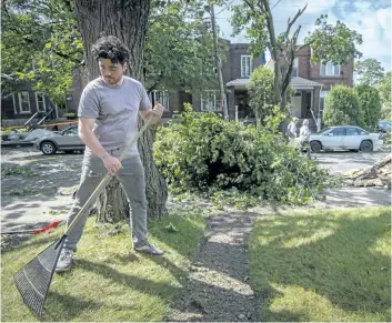  ?? PETER MCCABE/THE CANADIAN PRESS ?? Bruno Fortin cleans up after his neighbour’s roof was torn off and deposited on his front yard in the Montreal borough of Notre-Dame-de-Grace on Wednesday.
