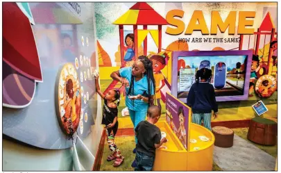  ?? (Special to the Democrat-Gazette/Arkansas Department of Parks, Heritage and Tourism, Kirk Jordan) ?? Jasmine Taylor Harris and her children Justice and Joshua place magnets on a wall at the new children’s gallery at Mosaic Templars Cultural Center while Pilar Primm explores different characters on a video screen. The gallery will celebrate its grand opening Saturday.