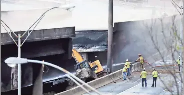  ?? David Goldman / The Associated Press ?? Crews work on a section of an overpass Friday that collapsed on Interstate 85 in Atlanta. A massive fire caused the bridge to collapse the day before, completely shutting down the heavily traveled highway.