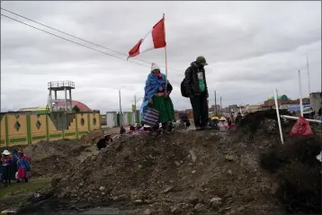  ?? PHOTOS BY RODRIGO ABD — THE ASSOCIATED PRESS FILE ?? An Aymara woman, holding a Peruvian national flag, stands on a pile of dirt serving as a roadblock set up by antigovern­ment protesters, in Acora, southern Peru, on Jan. 29. Peruvians have been protesting since early December, when former President Pedro Castillo was impeached after a failed attempt to dissolve Congress.