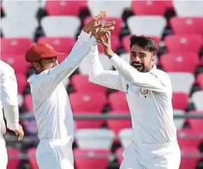  ?? AFP PIC ?? Afghanista­n’s Rashid Khan (right) celebrates with teammates after dismissing Ireland’s Kevin O’Brien on the third day of their Test match on Saturday.