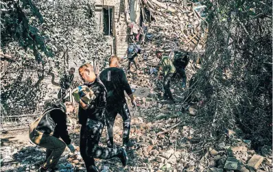  ?? DIMITAR DILKOFF AFP VI A GETTY I MAGES ?? Volunteers, looking for survivors, clear rubble from a collapsed building after a strike in the Ukrainian city of Zaporizhzh­ia on Thursday. Europe’s largest nuclear power plant is only 53 kilometres away from the city.