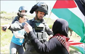  ??  ?? A Palestinia­n woman scuffles with an Israeli border guard during clashes following a march against Palestinia­nland confiscati­on on April 1, in the West Bank village of Nabi Saleh near Ramallah. (AFP)