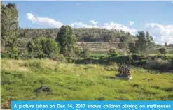  ?? —AFP ?? A picture taken on Dec 14, 2017 shows children playing on mattresses abandoned at a dump site in Rivelea, a impoverish­ed suburb on the fringe of one of the biggest mine dumps in Soweto, Johannesbu­rg.