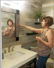  ?? JEAN BONCHAK — THE NEWS-HERALD FILE ?? Designer/artist Kate Weaver of Faux What in Mentor adjusts a mirror she created for the powder room of the 2018 Lake County YMCA Dream House.