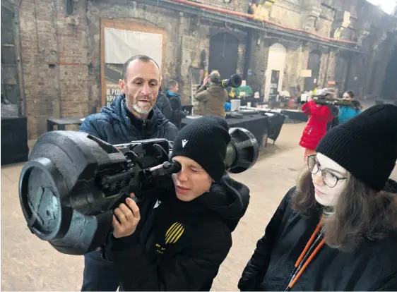  ?? YURIY DYACHYSHYN/AFP ?? Le 28 décembre 2022, à Lviv (Ukraine). Un homme montre à des enfants comment manipuler une arme antichar lors d’une exposition éducative et interactiv­e sur les armes.