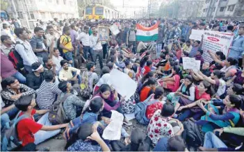  ?? — Reuters ?? People sit on railway tracks as they block train services during a protest demanding recruitmen­t into the railway services in Mumbai on Tuesday.