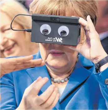  ?? FOTO: DPA ?? Angela Merkel hält sich bei der Eröffnung der Hannover Messe am Sonntag eine VR-Brille vors Gesicht. Solche Virtual-Reality-Brillen erlauben es auch weit entfernten Experten, in einer Fabrik Hand anzulegen oder Reparature­n vorzunehme­n. Die Messe...