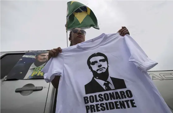 ?? FOTO: TT / AP / ERALDO PERES ?? En Bolsonaros­upporter säljer tröjor med tryck föreställa­nde sin kandidat vid en busstation i Brasilien.■