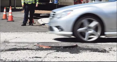  ?? Tyler Sizemore / Hearst Connecticu­t Media ?? A car dodges a raised manhole cover as paving begins on Summer Street in Stamford on Thursday. Many residents have suffered flat tires from the raised manhole covers on the road, comparing it to an obstacle course.