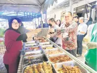 ?? ?? SILA PAKAI: Wan Samsulri mengagihka­n apron kepada peniaga Bazar Ramadan Meditel 2024.