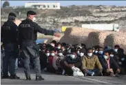  ??  ?? Italian police watch over new arrivals on Lampedusa.