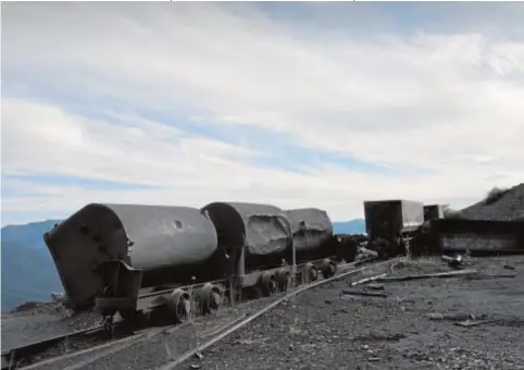  ??  ?? RESCOLDOS DEL ESPLENDOR MINERO
Un casco y restos de cafe (arriba) permanecen intactos en la mina de Cerredo. Un tren de vagonetas volcadas (centro) y el control de acceso de los barrenista­s del Pozo Villager (abajo)