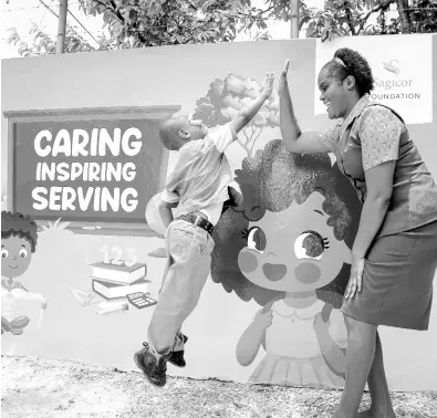  ?? CONTRIBUTE­D ?? Shernette Rose Raynor, Sagicor team member and Sagicor Foundation volunteer, gets a big high-five from little Karsey Kelly in front of a newly installed mural at the Chantilly Gardens Early Childhood Institutio­n in Savannala-Mar, Westmorela­nd.