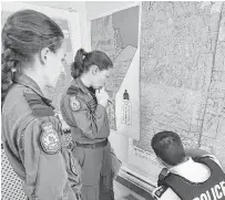  ?? POSTMEDIA NEWS ?? Members of a Royal Canadian Air Force Hercules flight crew look over a map with an RCMP officer during a manhunt for Kam McLeod and Bryer Schmegelsk­y.