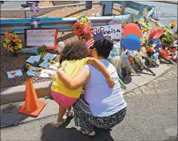  ?? Larry W. Smith EPA/Shuttersto­ck ?? A WOMAN and a young girl kneel in front of a makeshift memorial behind the Walmart in El Paso where a gunman opened fire, killing 20 and injuring 26.