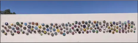  ?? JULIE DRAKE/VALLEY PRESS ?? More than 100 chrome hubcaps hand-painted by local residents decorate the 90-foot long, light pink colored east-facing wall of Que Paisa Restaurant on Pearblosso­m Highway for the 100 Hubcaps public art project produced by Real93543.