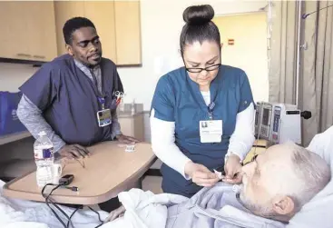  ?? Brett Coomer / Houston Chronicle ?? David Raven, left, and Anya Montoya work with patient Neil Harrison at Houston Methodist Cancer Center on Friday. As energy companies expect more layoffs, the health care sector continues to see robust hiring.