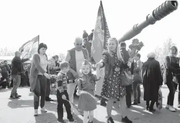  ?? ALEXEI ALEXANDROV/AP ?? Ukraine remembers: A girl wearing Soviet-era military uniform and her relatives walk during Victory Day celebratio­ns Saturday at a World War II memorial in Saur-Mogila, Ukraine, near the Russian border. Efforts have stalled to end the conflict between Russia-backed rebels and Ukrainian forces that’s killed more than 14,000 people since 2014.