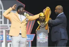  ?? David Richard / Associated Press ?? LaDainian Tomlinson, left, and his presenter Lorenzo Neal unveil his bust before his speech at the Hall of Fame.