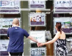  ?? — AFP ?? A couple view properties for sale in an estate agents window in London.