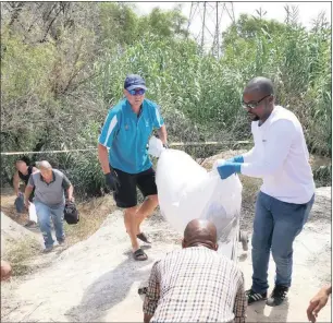  ?? GRUESOME FIND: Soraya Crowie ?? Forensic pathologis­ts carry the body of a badly decomposed man which was found in a ditch amongst dense reeds behind Beacon Primary School in Colville on Saturday.Picture: