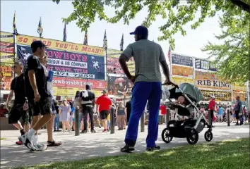  ?? Steve Mellon/Post-Gazette photos ?? Nicholas Clark, with 10-month-old daughter Rosemary in a stroller, checked out the choices at the Heinz Field Kickoff and Rib Fest on the North Shore on Monday. The Clark family recently moved from New Orleans to Pittsburgh’s North Side.