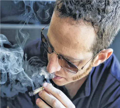  ?? RICHARD VOGEL • AP ?? Judd Weiss takes a puff of a pre-rolled marijuana cigarette at his house in the Bel Air section of Los Angeles. Weiss is CEO and founder of cannabis company Lit.club.